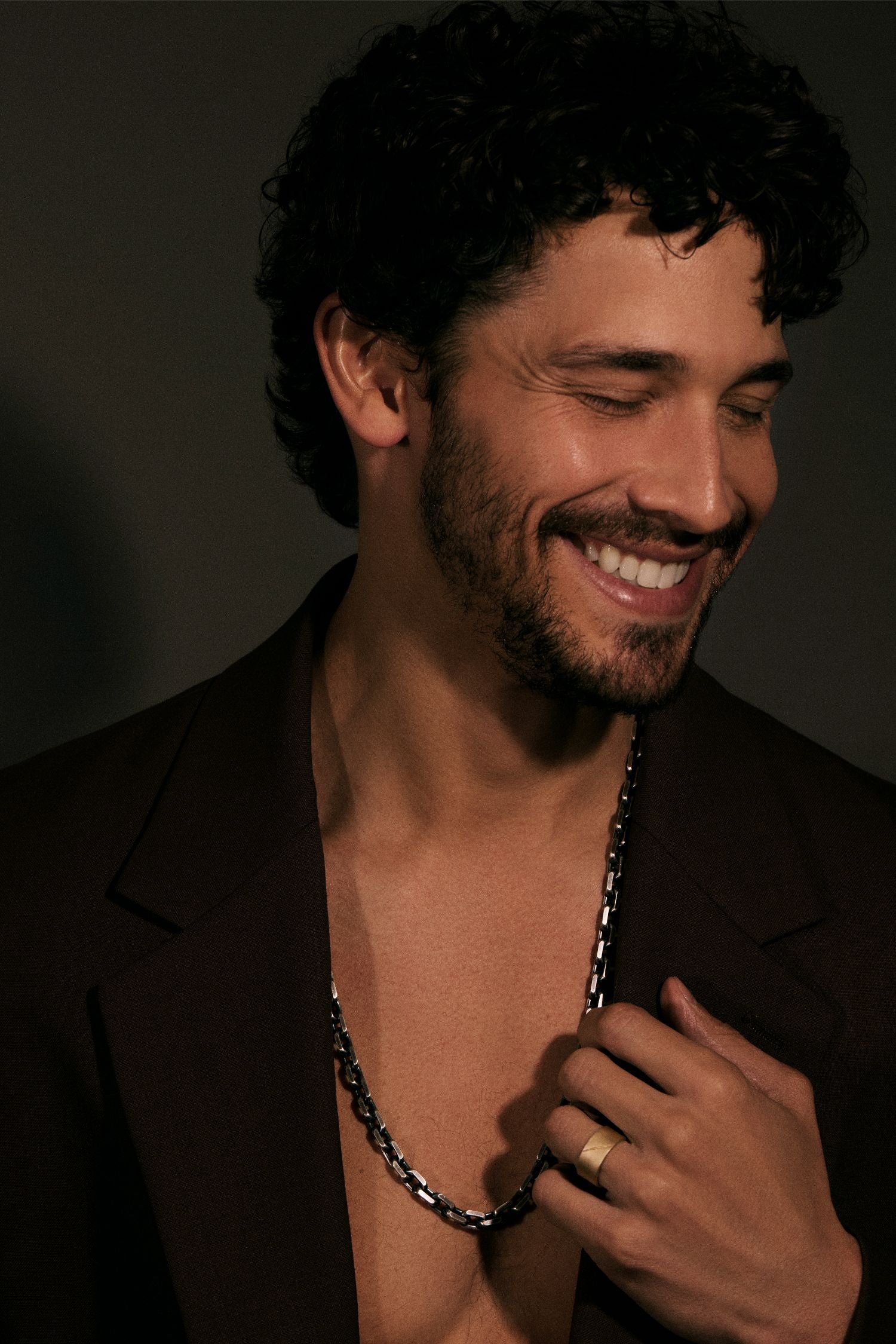 Man with a beard and necklace against a dark background