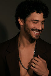Man with a beard and necklace against a dark background
