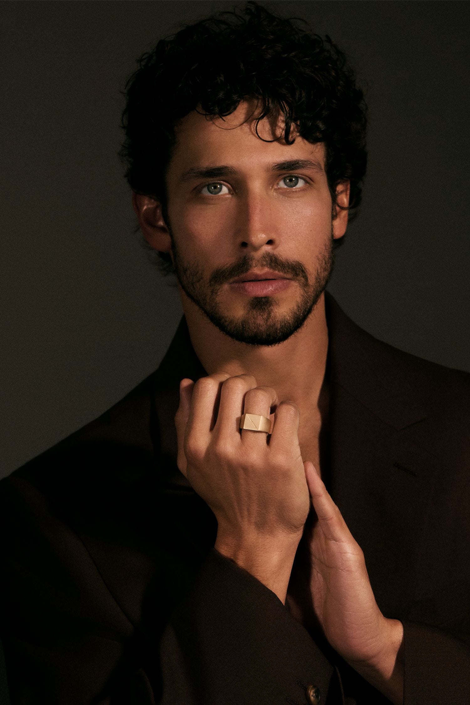 Man wearing a gold ring with a dark background
