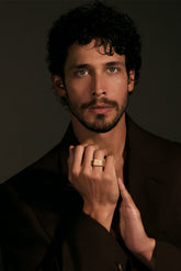 Man wearing a gold ring with a dark background