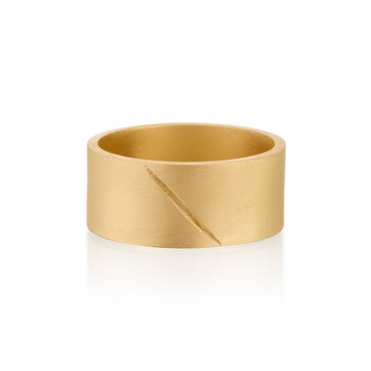 Gold band ring with an etched scar on a white background