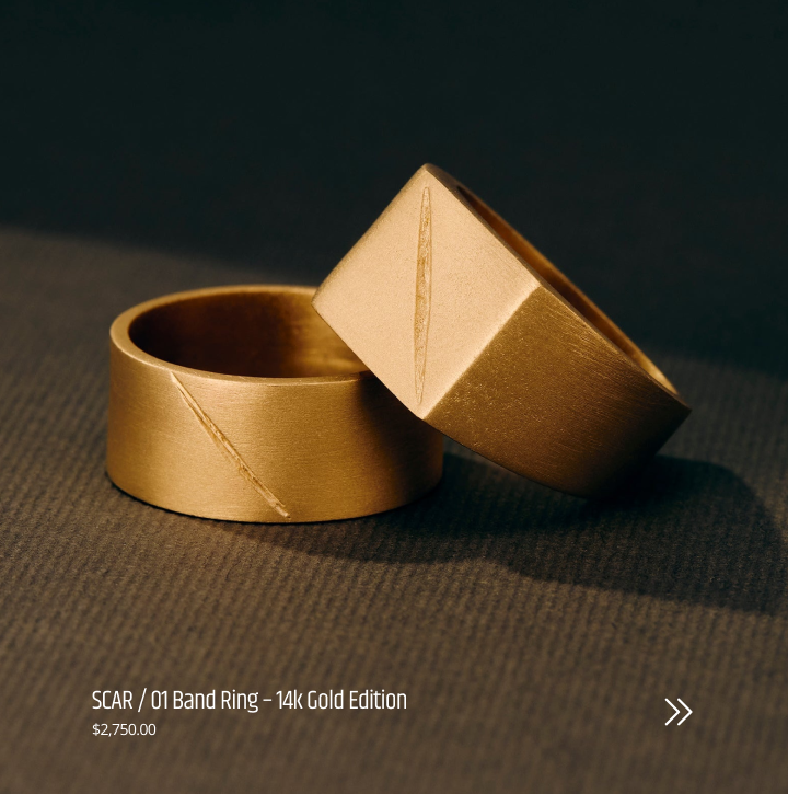 Gold band ring and a signet ring with a box on a dark surface part of the  MZNR SCAR / 01 collection